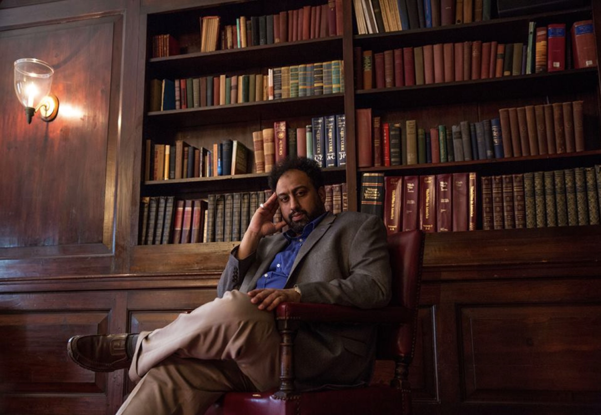 Isma'il Kushkush seated in a wood-panelled library